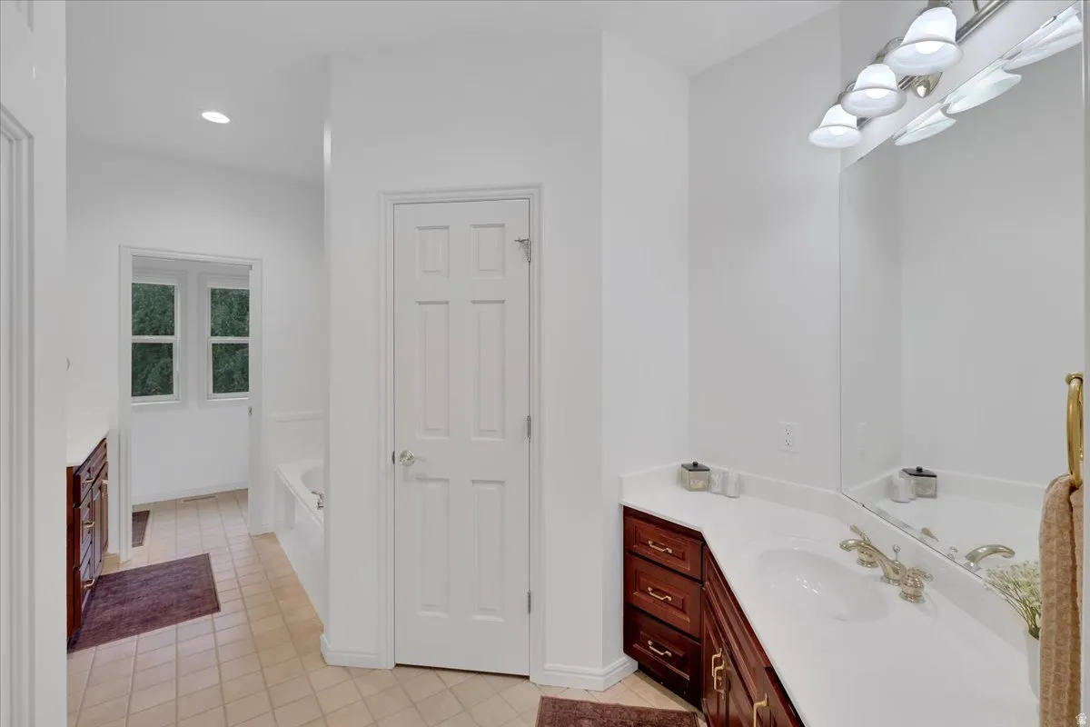 Bathroom featuring a single vanity with a white countertop, an undermount sink, and a large wall mirror