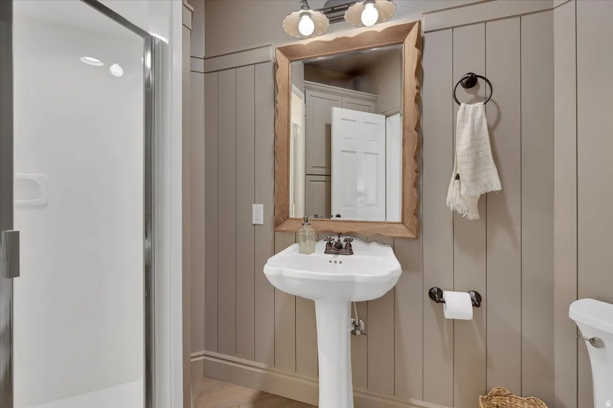 Pedestal sink with bronze faucet and a decorative wood-framed mirror
