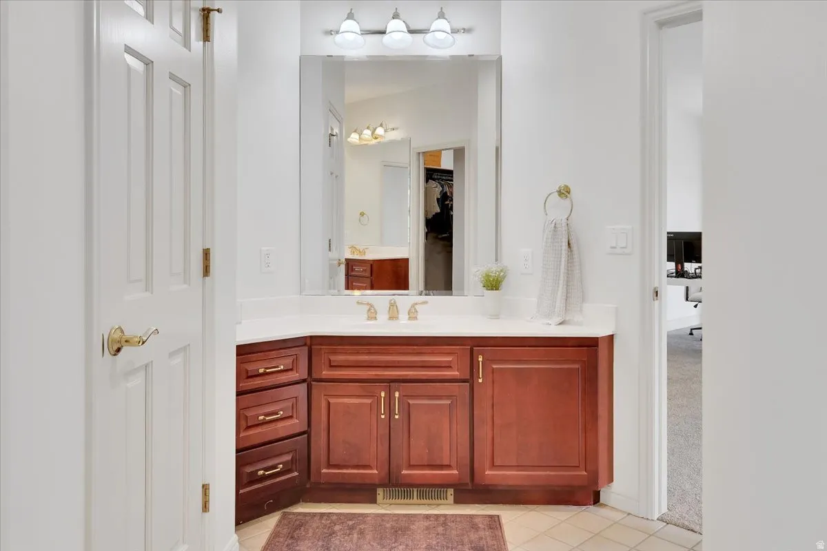 Bathroom vanity featuring a light-colored countertop, integrated sink, and gold-finish fixtures