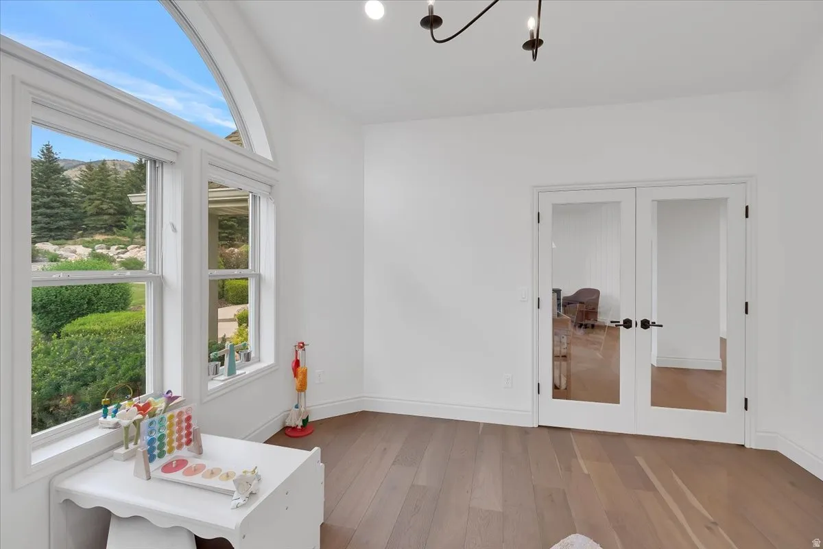 Room featuring large windows with an arched transom, wood-finish flooring, white walls, and a contemporary ceiling fixture