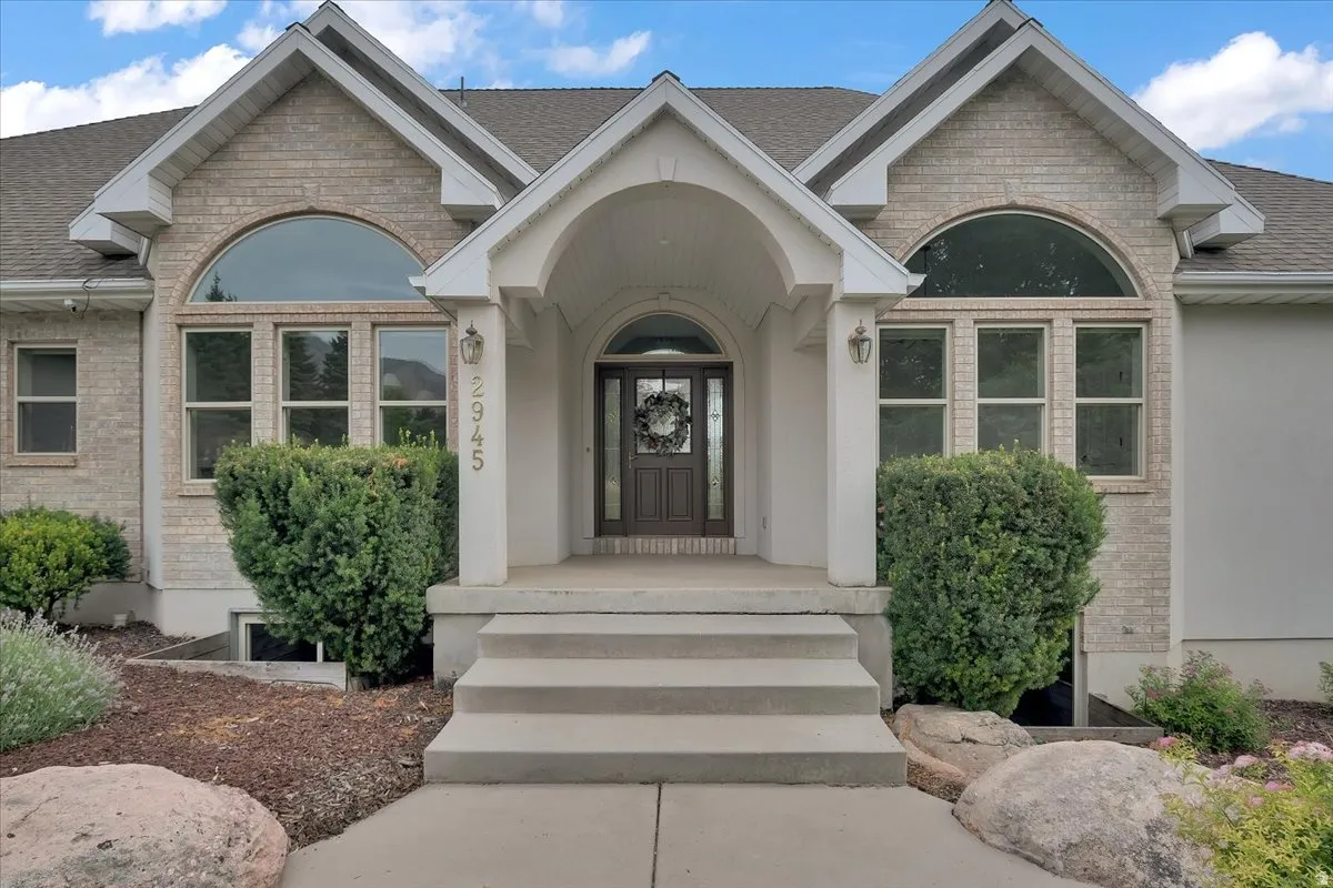 Brick and stucco exterior featuring an arched entryway with a dark wood-finish door