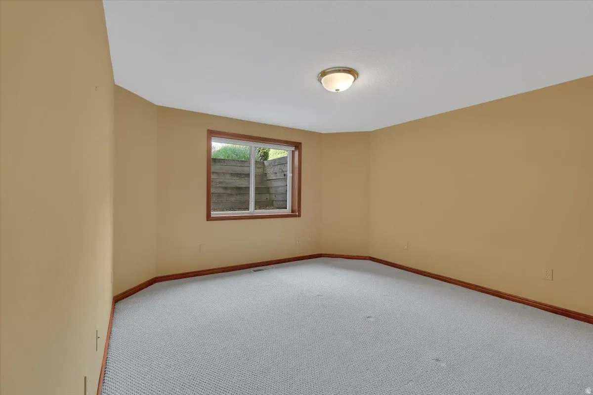 Spacious room featuring neutral-toned walls, light-colored textured carpeting, and wood-finish trim