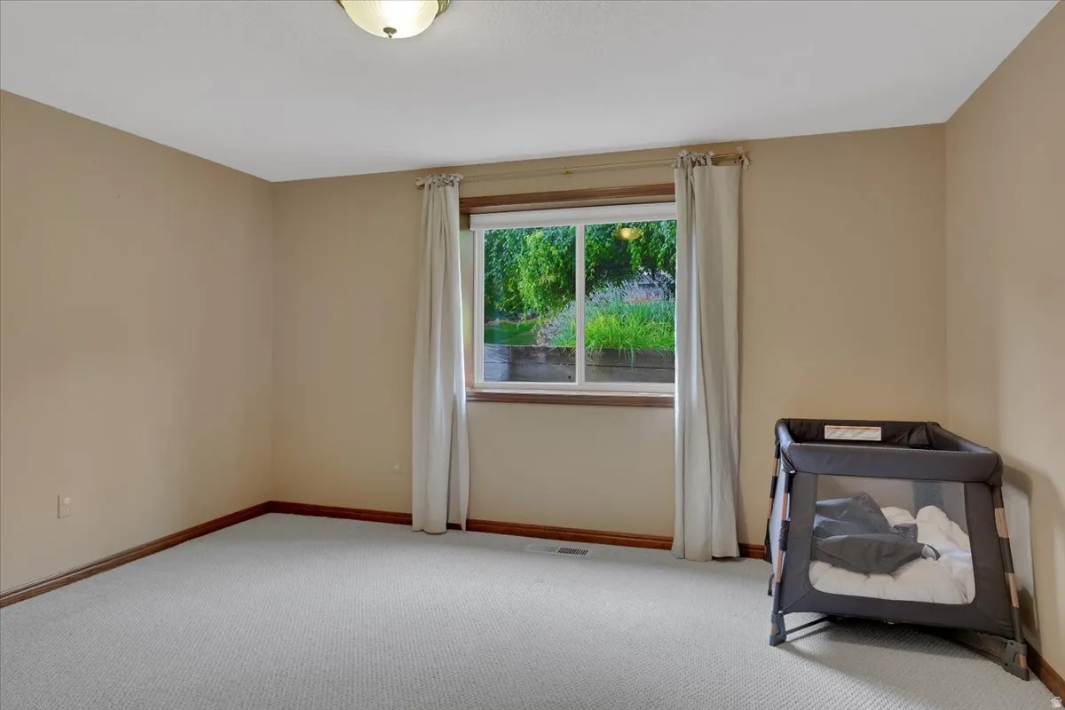Bright room featuring light-colored walls, a window with wood trim, and light-toned carpeting