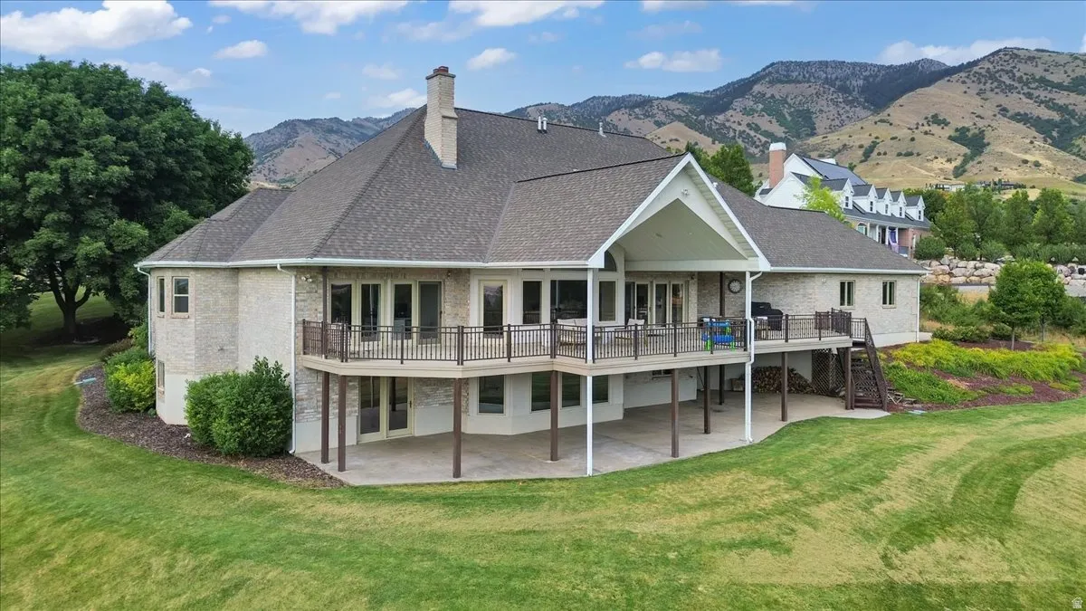 Stone exterior with an expansive upper-level deck, covered patio, and multi-level landscaping