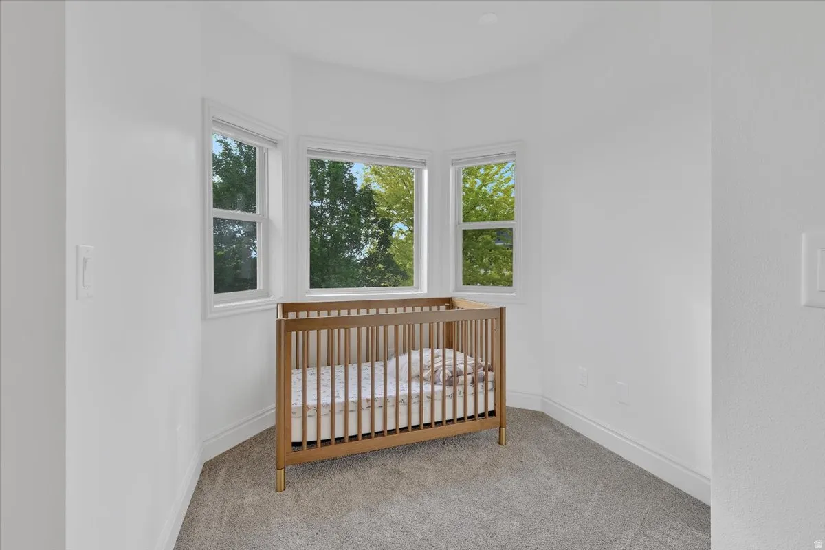 Bright room featuring a bay window with white trim, light gray carpeting, and clean white walls