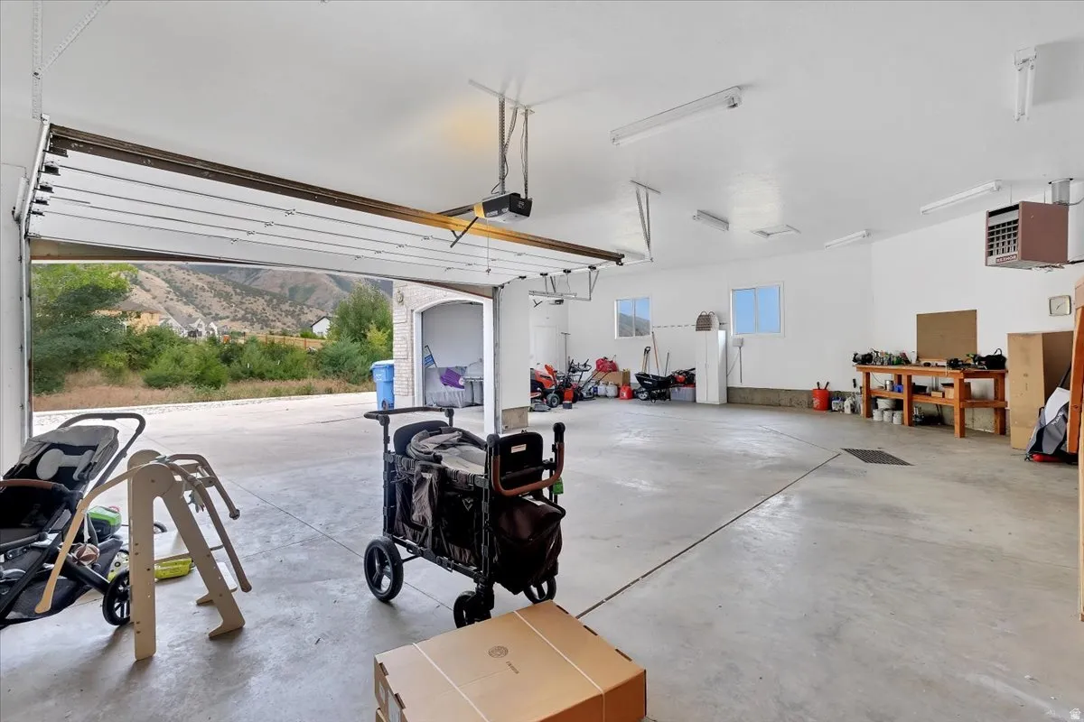 Spacious multi-car garage featuring a concrete floor, white walls, and overhead fluorescent lighting