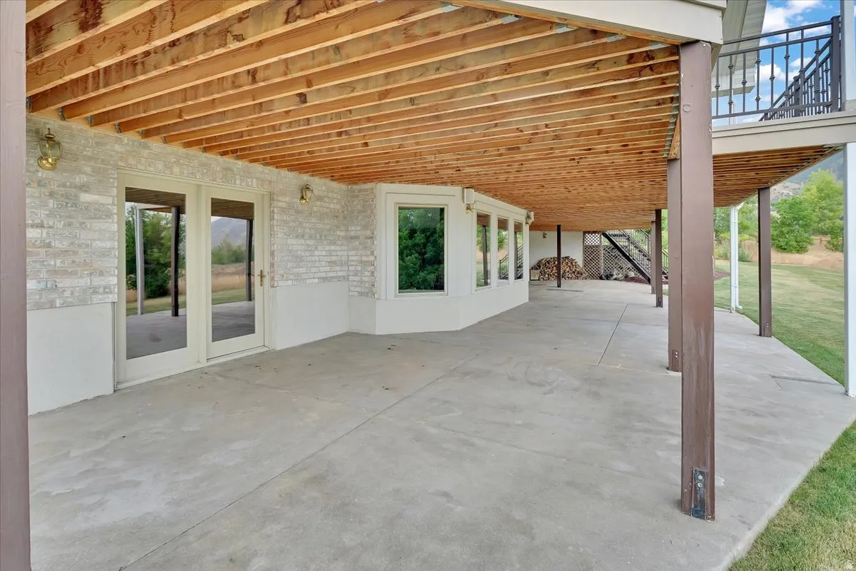 Spacious covered concrete patio with an exposed wood ceiling and recessed lighting