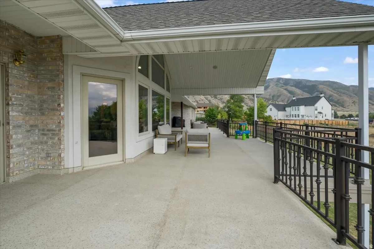 Spacious covered patio featuring a textured concrete surface, white trim, and a decorative metal railing