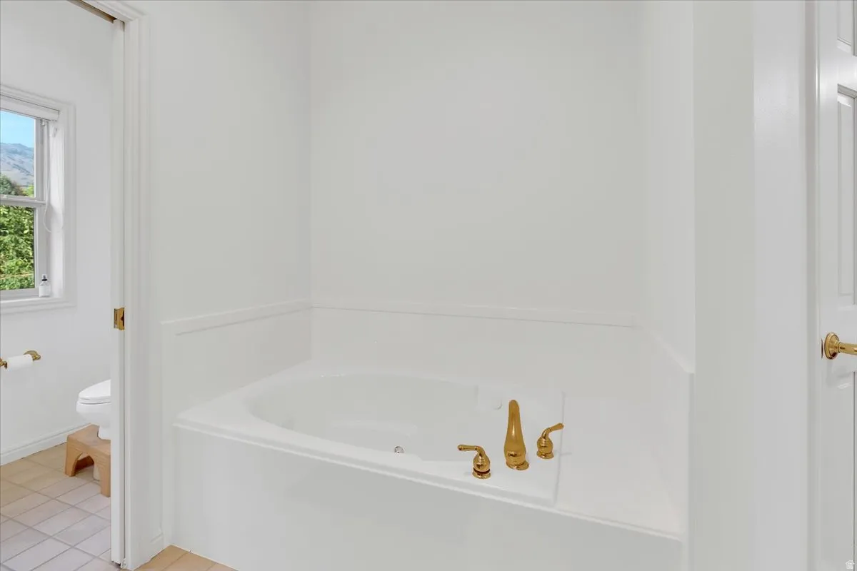 Built-in soaking tub with polished brass fixtures and wainscoting detail