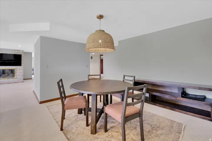 Dining area featuring a woven pendant light fixture, a built-in wood-finish media console, and light-toned carpeting