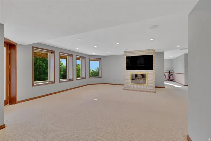 Expansive lower-level room featuring a light brick-faced fireplace with an integrated television niche