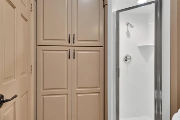 Integrated shower with glass enclosure, chrome fixtures, and a corner shelf