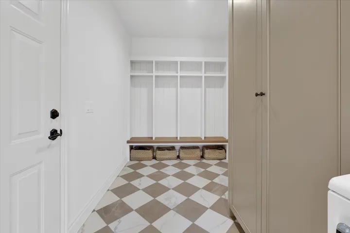 Mudroom featuring a built-in white storage system with individual cubbies and a wood bench