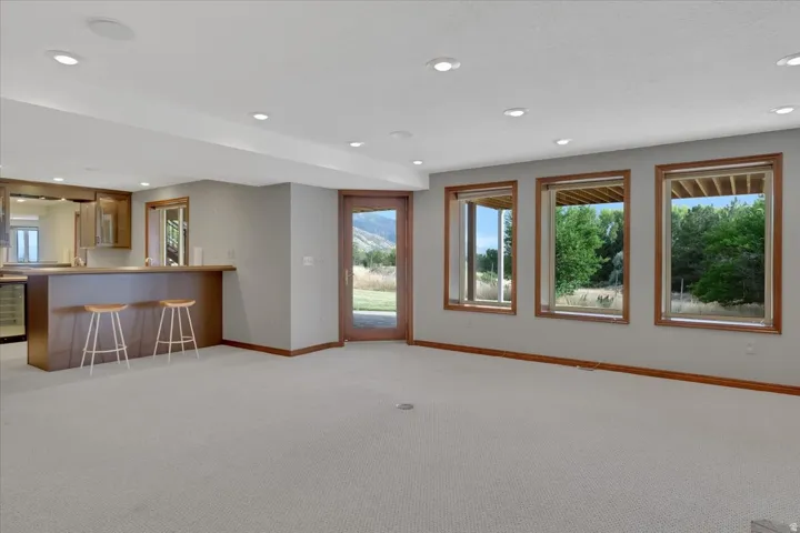 Spacious recreational room featuring a built-in wet bar with wood cabinetry, integrated beverage refrigerator, and a light-toned countertop