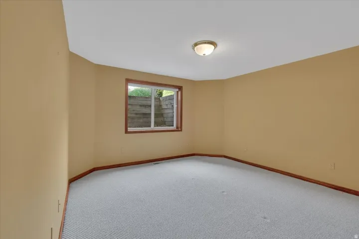 Spacious room featuring neutral-toned walls, light-colored textured carpeting, and wood-finish trim