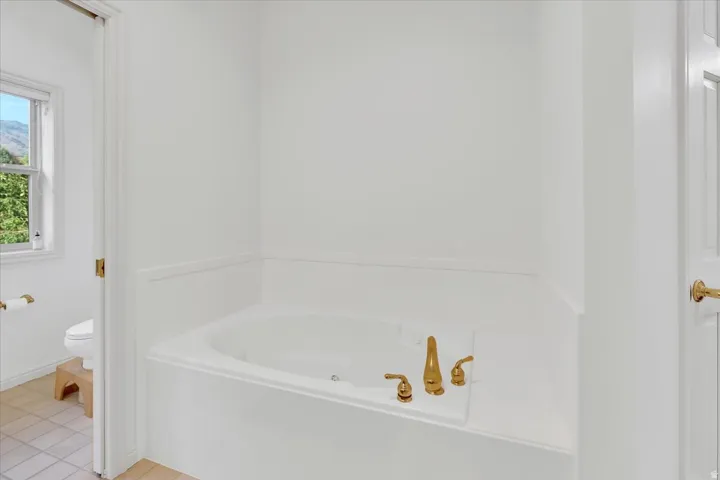 Built-in soaking tub with polished brass fixtures and wainscoting detail