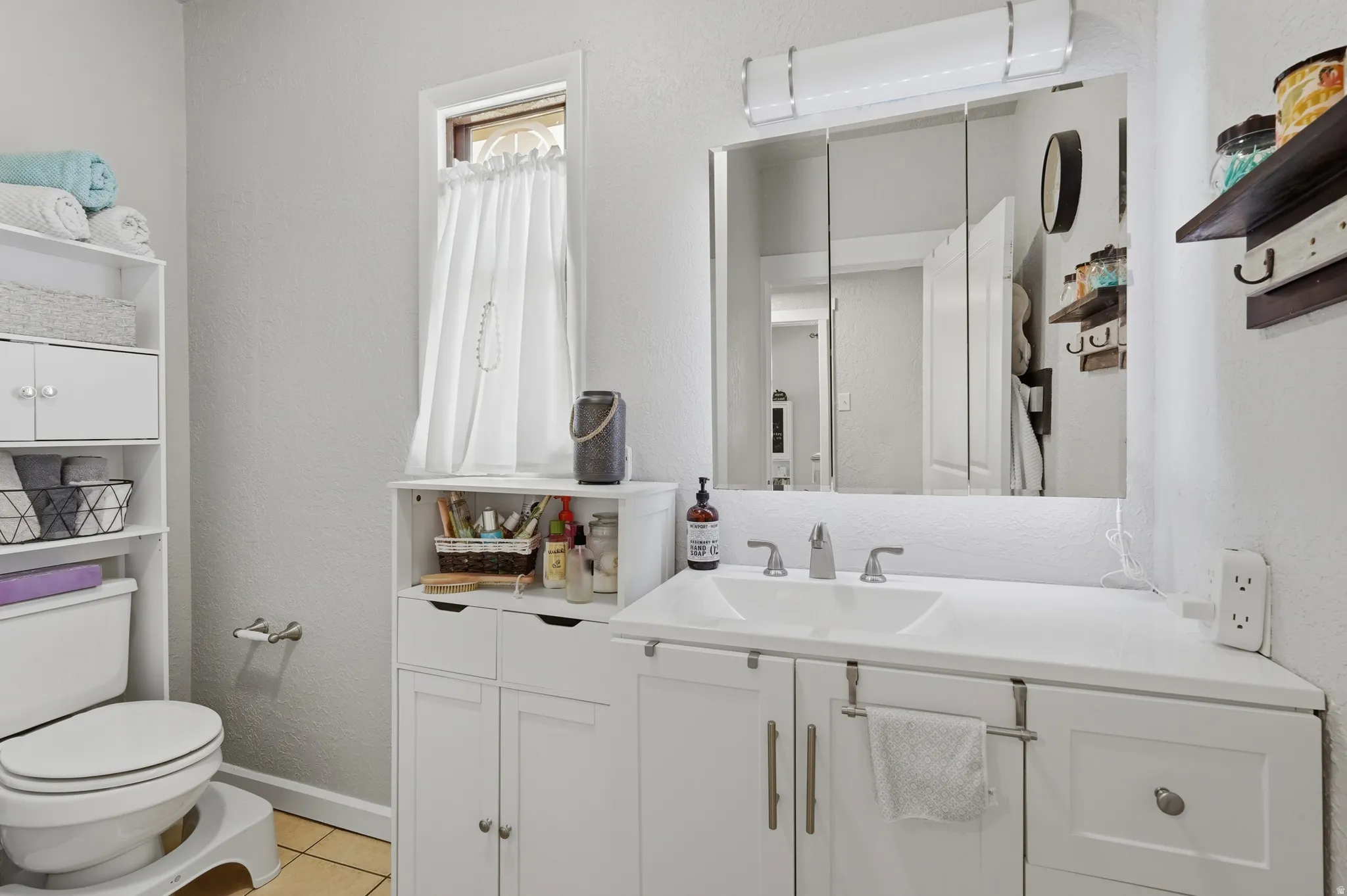 Bathroom featuring a white vanity with an integrated sink, brushed nickel faucet, and a large mirrored medicine cabinet