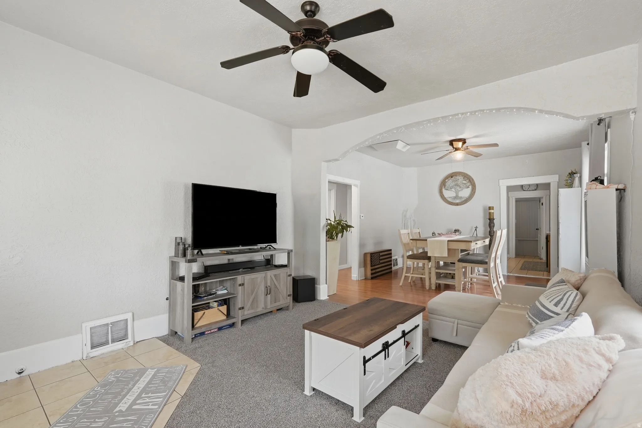 Living area featuring gray carpeting, a ceiling fan with integrated lighting, and light-toned wall finishes
