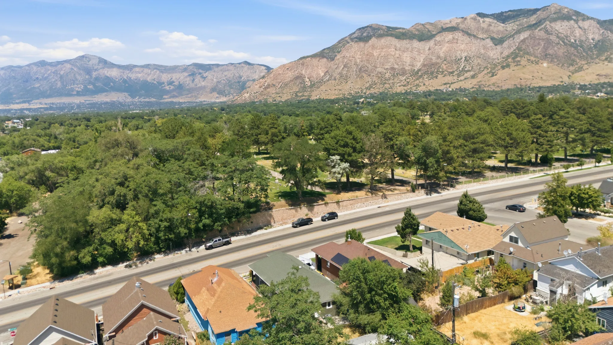 Expansive mountain backdrop featuring residential properties, a multi-lane roadway, and extensive mature trees