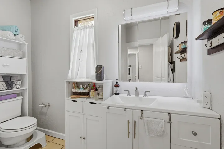 Bathroom featuring a white vanity with an integrated sink, brushed nickel faucet, and a large mirrored medicine cabinet