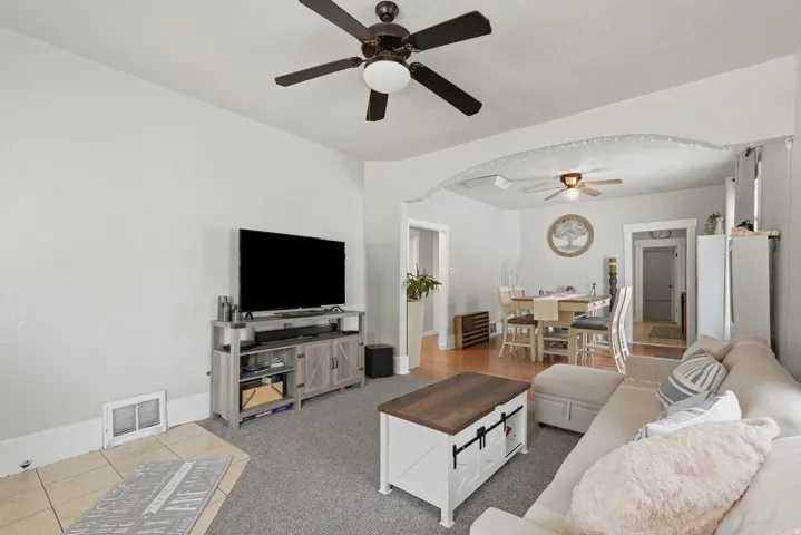 Living area featuring gray carpeting, a ceiling fan with integrated lighting, and light-toned wall finishes