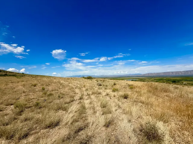 Expansive land parcel featuring dry grasses and a clear blue sky