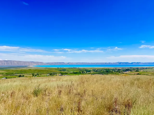 Expansive natural landscape featuring a broad body of water and distant mountains