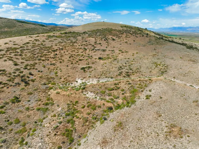 Expansive undeveloped land featuring natural desert vegetation, rolling hills, and distant mountain ranges
