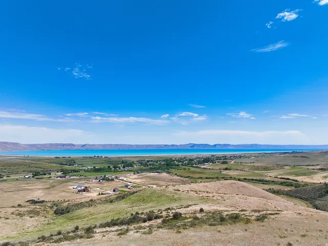 Expansive landscape featuring a large body of water, rolling hills, and scattered residential properties