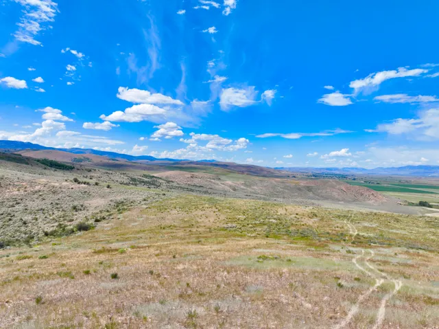 Expansive open landscape featuring rolling hills, distant mountain ranges, and natural vegetation