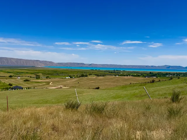 Expansive green landscape with distant mountains and a blue body of water