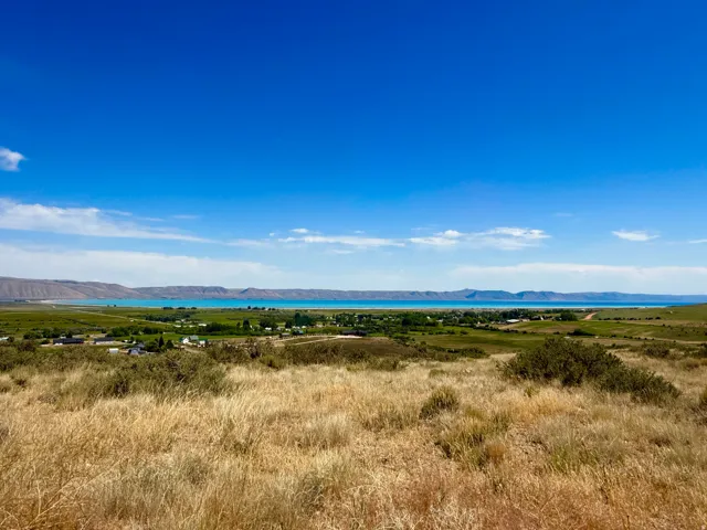 Expansive natural landscape featuring rolling hills and a distant body of water