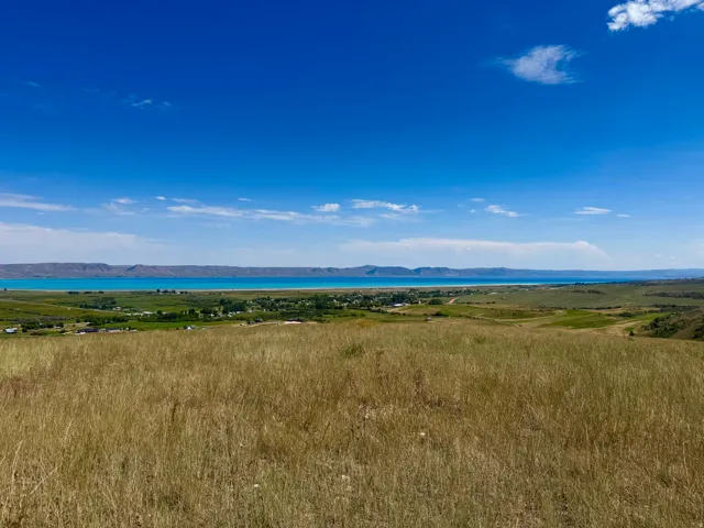 Expansive rural landscape featuring a body of water and distant mountains under a clear sky