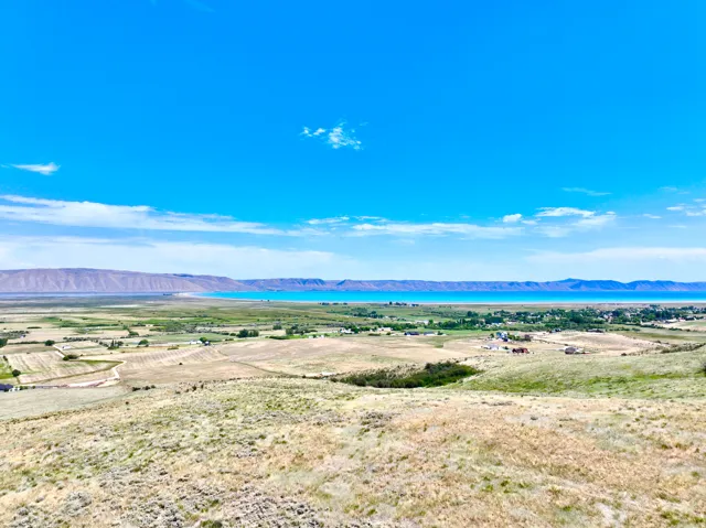 Expansive landscape featuring distant mountains, a large body of water, and scattered structures across a vast plain