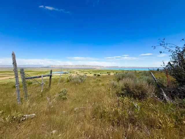 Expansive landscape featuring distant mountains, a body of water, and a clear blue sky