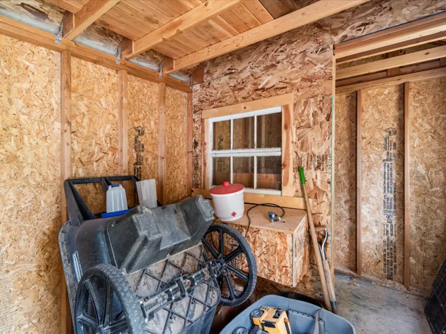 Utility structure featuring wood-finish walls, exposed wood ceiling beams, and a framed window with grid inserts