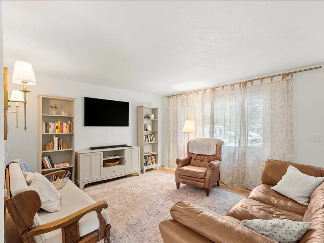 Living room featuring wood-finish flooring and a large window with sheer curtains