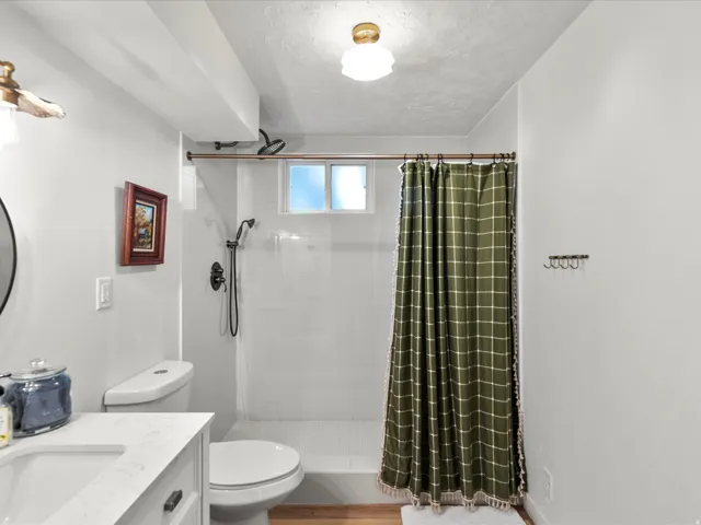 Contemporary bathroom featuring a white vanity with integrated sink, dark hardware, and a white toilet