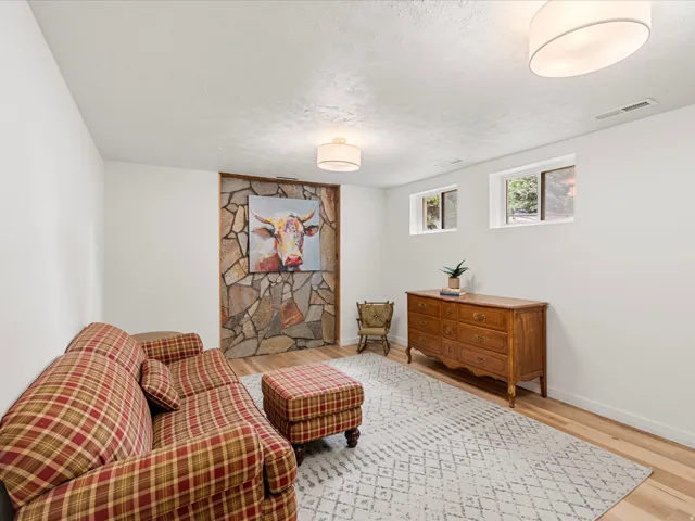 Spacious room featuring light wood-finish flooring, a decorative stone wall accent, and two ceiling-mounted drum light fixtures