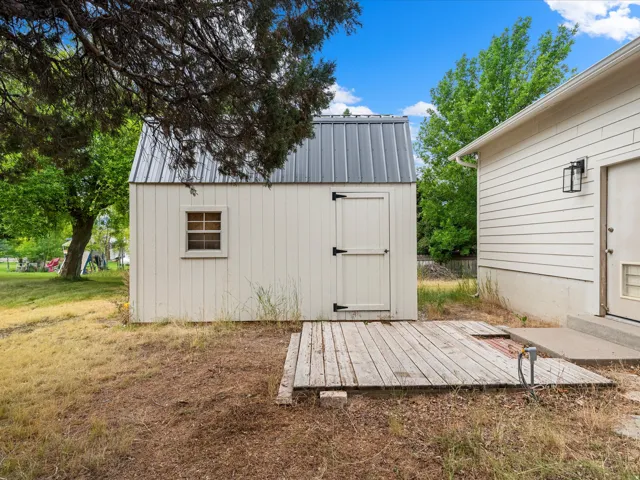 White utility shed featuring a metal roof and a small window