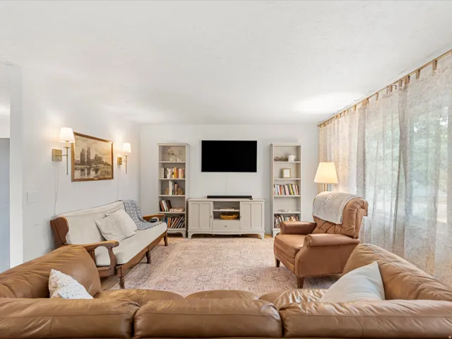 Living area featuring white walls, sconce lighting, and sheer window treatments