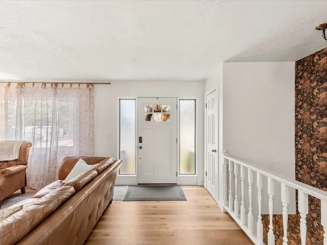 Entryway featuring light wood-finish flooring, a white door with decorative glass panels, and frosted sidelight windows
