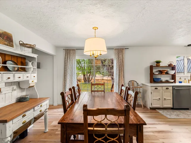 Spacious dining area featuring wood-finish flooring, a contemporary chandelier, and a large sliding glass door