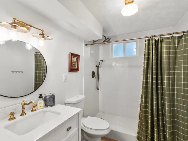 White vanity with a rectangular undermount sink, brass-finish faucet, and stone-finish countertop