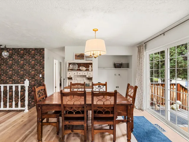 Dining area featuring wood-finish flooring, a contemporary chandelier, built-in shelving, and a sliding glass door providing exterior access