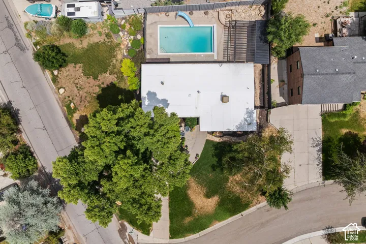 Aerial perspective showcasing the property's rectangular swimming pool with a slide, surrounded by a paved patio area