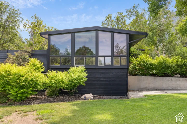 Modern architectural design featuring a prominent window wall, dark exterior siding, and a pitched roofline