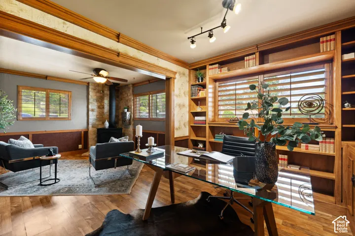 Expansive room featuring wood-finish flooring, a built-in wall of cabinetry, wood window frames with horizontal blinds, and a stone accent wall