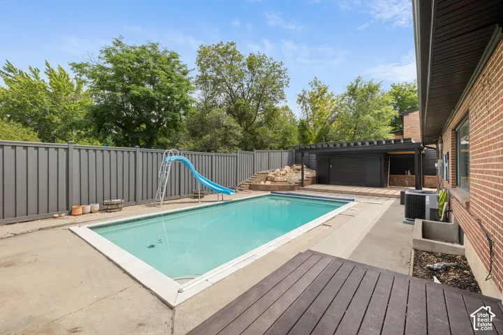 Backyard swimming pool with surrounding concrete patio and privacy fencing