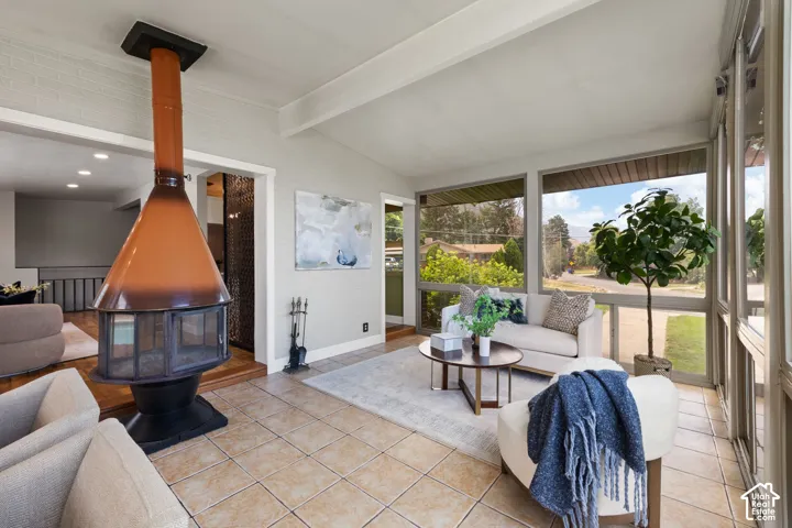 Spacious sunroom featuring a prominent freestanding fireplace with a copper-tone hood